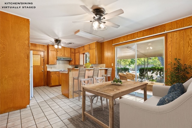 interior space with wood walls, ceiling fan, and light tile patterned floors