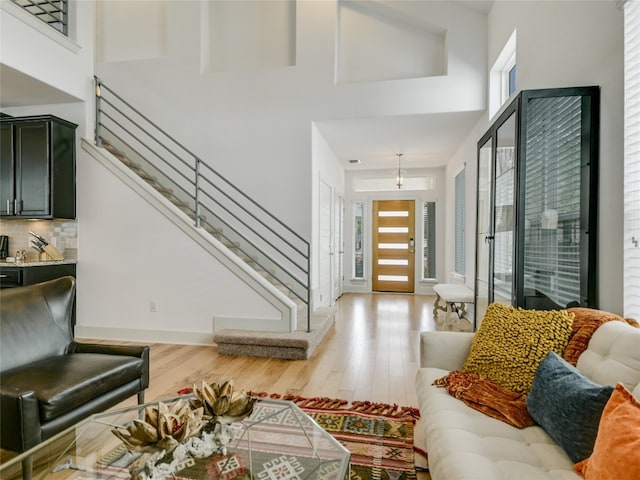 living room with an inviting chandelier, light hardwood / wood-style floors, and a high ceiling