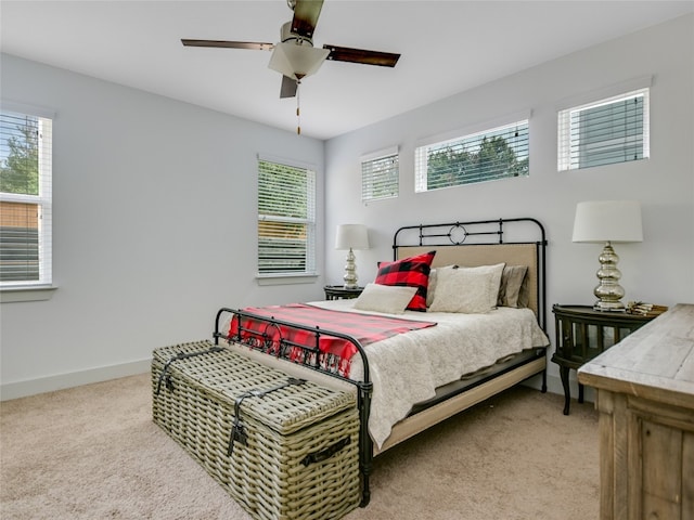 bedroom with light carpet, ceiling fan, and multiple windows