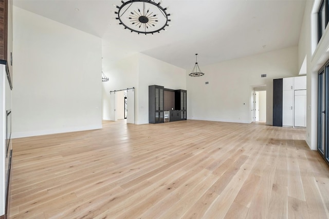 unfurnished living room with light hardwood / wood-style floors and a towering ceiling