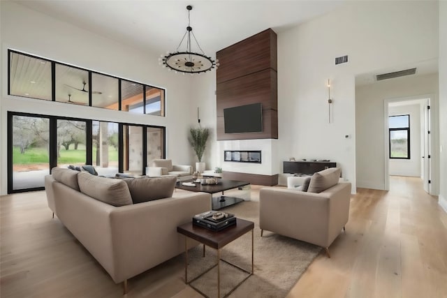 living room with an inviting chandelier, a high ceiling, and light hardwood / wood-style floors