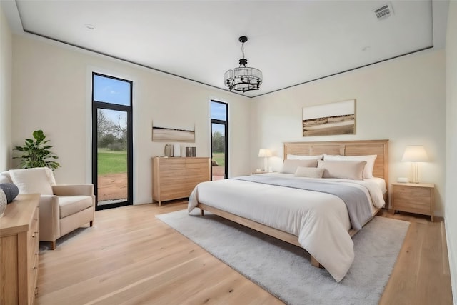 bedroom with a notable chandelier, access to exterior, and light hardwood / wood-style flooring