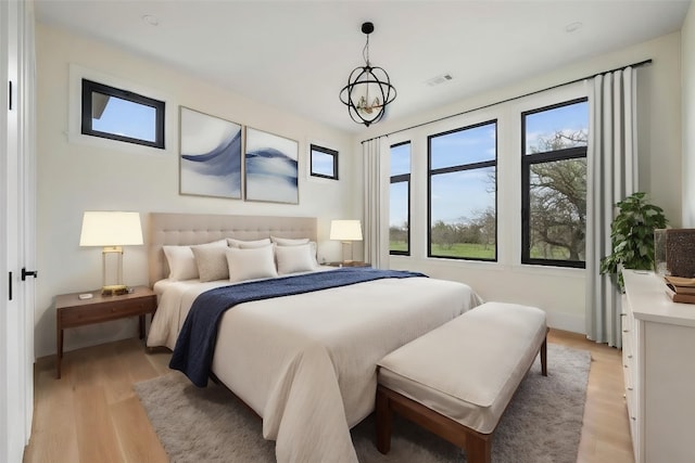 bedroom with multiple windows, light hardwood / wood-style flooring, and an inviting chandelier