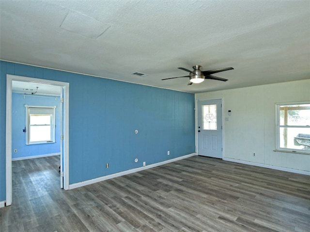 unfurnished room with a textured ceiling, ceiling fan, and dark wood-type flooring