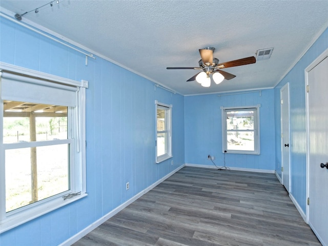 spare room featuring ceiling fan, a wealth of natural light, dark wood-type flooring, and a textured ceiling