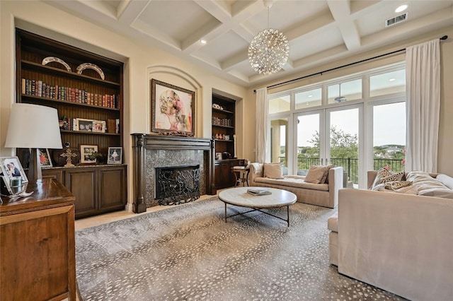 living room featuring a high end fireplace, built in features, an inviting chandelier, and coffered ceiling