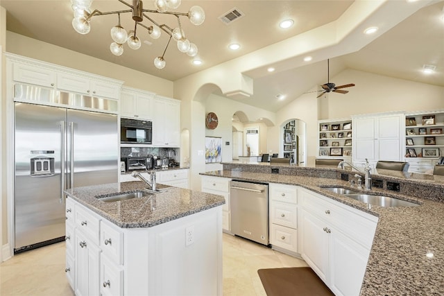 kitchen featuring a kitchen island with sink, sink, appliances with stainless steel finishes, ceiling fan with notable chandelier, and white cabinetry