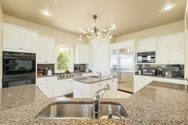 kitchen with tasteful backsplash, a center island with sink, a notable chandelier, and appliances with stainless steel finishes