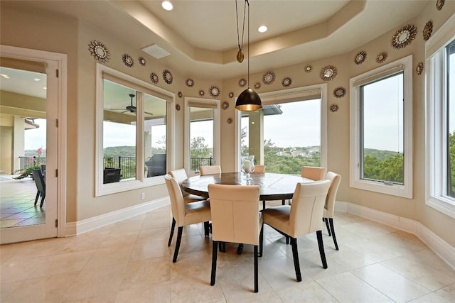 tiled dining room featuring a raised ceiling and ceiling fan