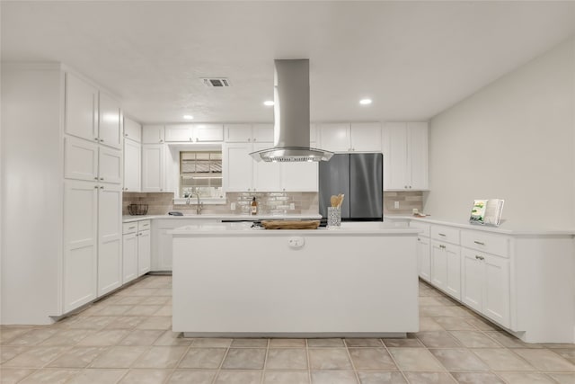 kitchen with island exhaust hood, a center island, white cabinetry, and stainless steel fridge