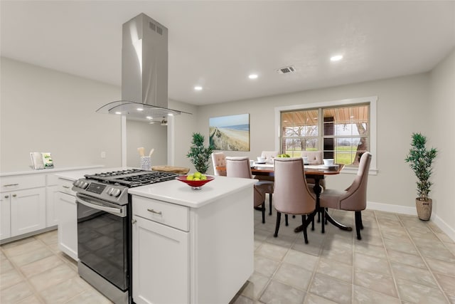 kitchen with white cabinets, stainless steel range with gas cooktop, light tile floors, and island exhaust hood