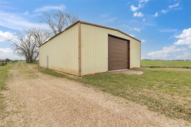 view of shed / structure with a yard, a garage, and a rural view