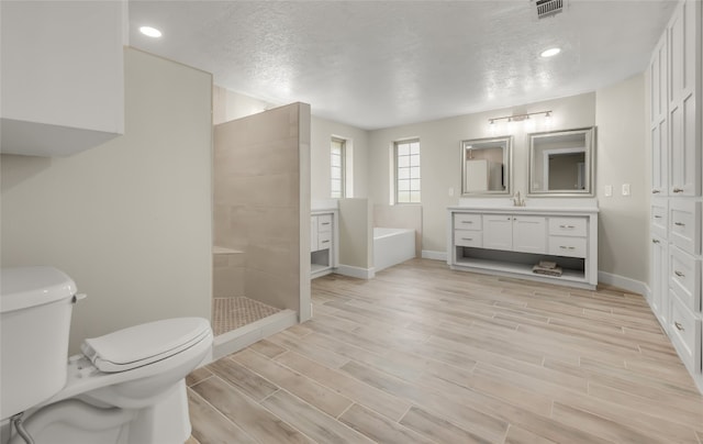 full bathroom with toilet, hardwood / wood-style flooring, a textured ceiling, vanity, and shower with separate bathtub