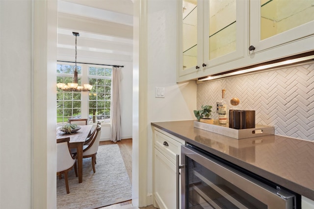 bar featuring pendant lighting, white cabinets, beverage cooler, light hardwood / wood-style floors, and a notable chandelier