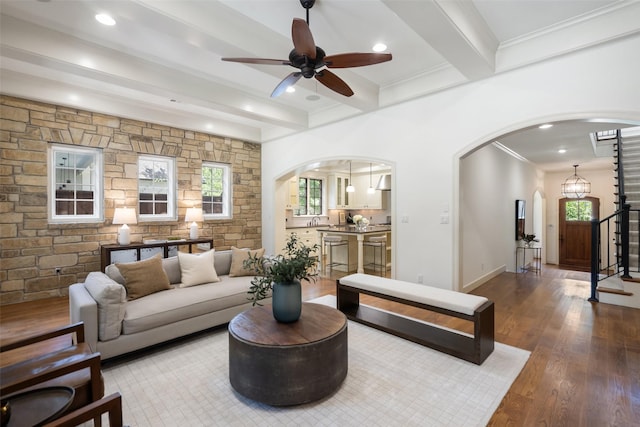 living room with ceiling fan, beamed ceiling, ornamental molding, and hardwood / wood-style floors