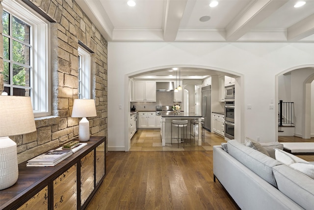 living room featuring ornamental molding, dark hardwood / wood-style flooring, beam ceiling, and a healthy amount of sunlight