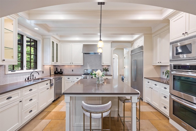 kitchen featuring a kitchen bar, decorative backsplash, built in appliances, a kitchen island, and pendant lighting