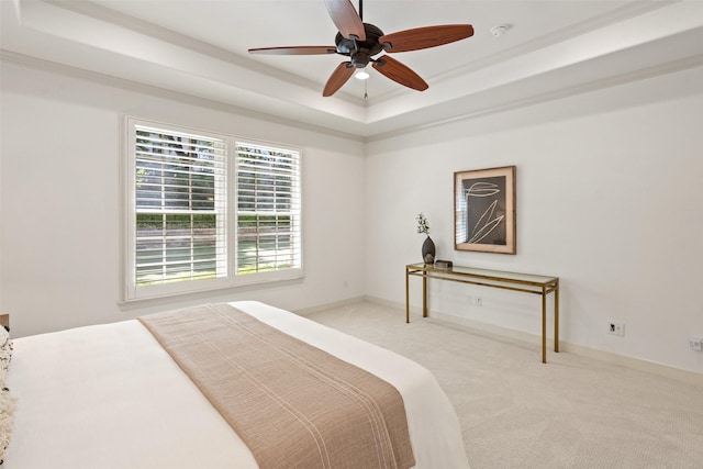 carpeted bedroom featuring ceiling fan, crown molding, and a raised ceiling