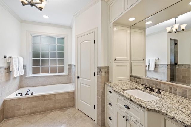 bathroom with tiled bath, vanity, a notable chandelier, tile patterned floors, and ornamental molding