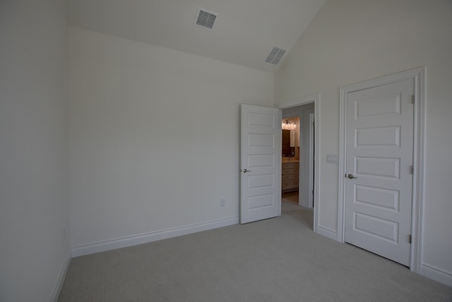 unfurnished room featuring lofted ceiling and light colored carpet