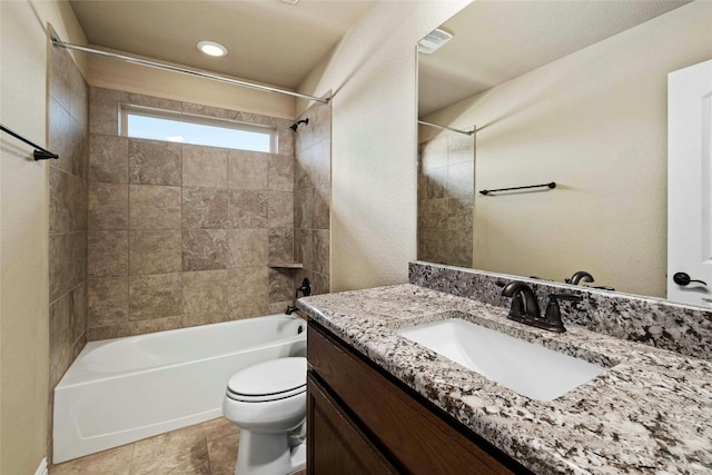 full bathroom featuring tile floors, toilet, large vanity, and tiled shower / bath combo