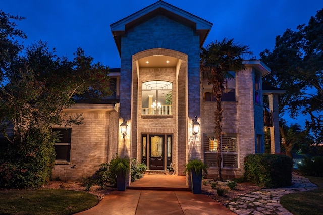 exterior entry at twilight with french doors and a balcony