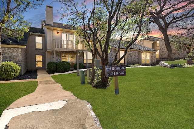 view of front of home with a balcony and a yard