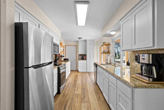 kitchen with stainless steel appliances, light wood-type flooring, white cabinets, and sink