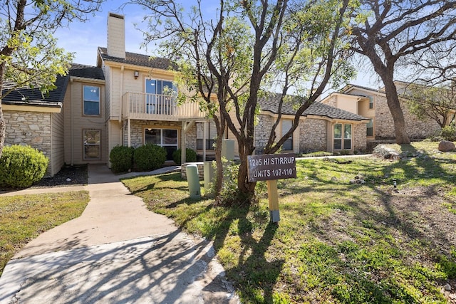 view of front facade featuring a front lawn and a balcony