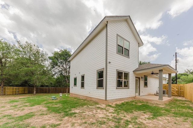 rear view of house featuring ceiling fan, a lawn, and a patio