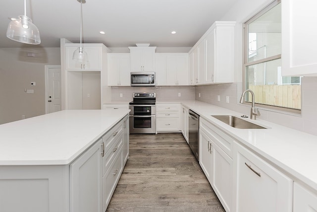 kitchen featuring decorative light fixtures, sink, white cabinetry, and stainless steel appliances