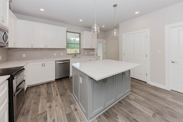 kitchen featuring white cabinetry, decorative backsplash, a kitchen island, pendant lighting, and stainless steel appliances