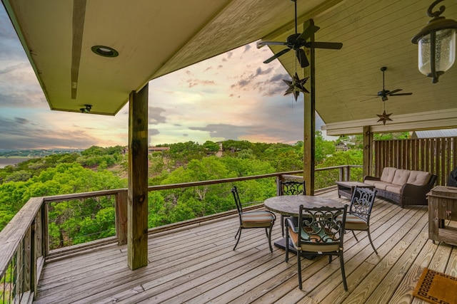 deck at dusk with outdoor lounge area and ceiling fan