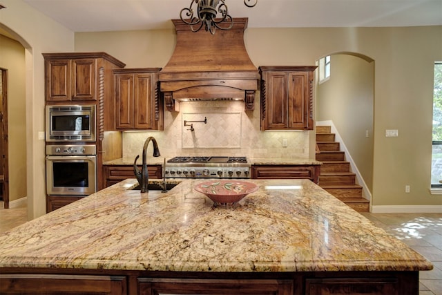 kitchen with plenty of natural light, an island with sink, backsplash, and appliances with stainless steel finishes