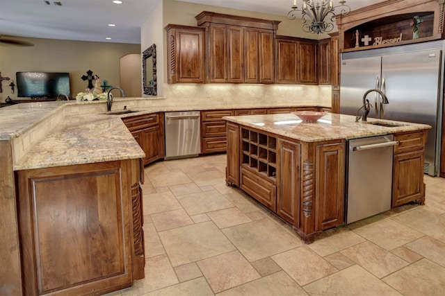 kitchen with kitchen peninsula, a notable chandelier, appliances with stainless steel finishes, sink, and a center island