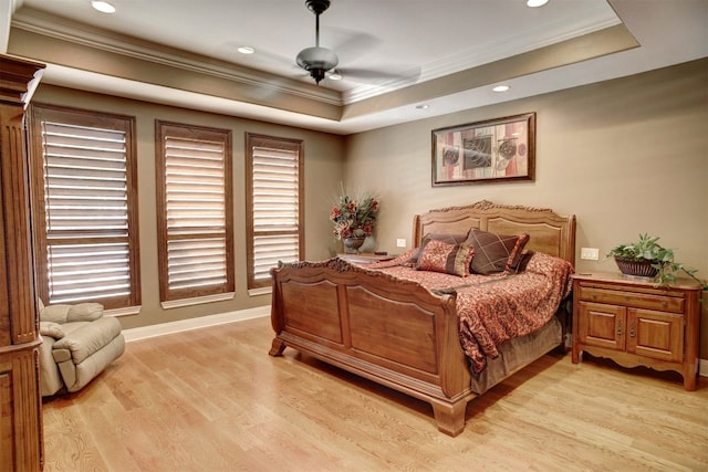 bedroom with ceiling fan, crown molding, a raised ceiling, and light hardwood / wood-style flooring