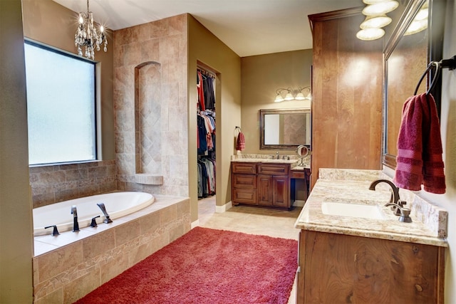 bathroom featuring tile floors, a notable chandelier, a relaxing tiled bath, and vanity with extensive cabinet space