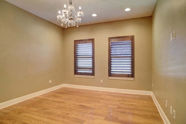 spare room with light hardwood / wood-style floors, a notable chandelier, and a wealth of natural light