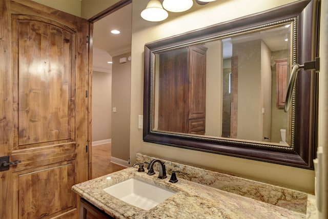 bathroom with crown molding, vanity with extensive cabinet space, and hardwood / wood-style flooring