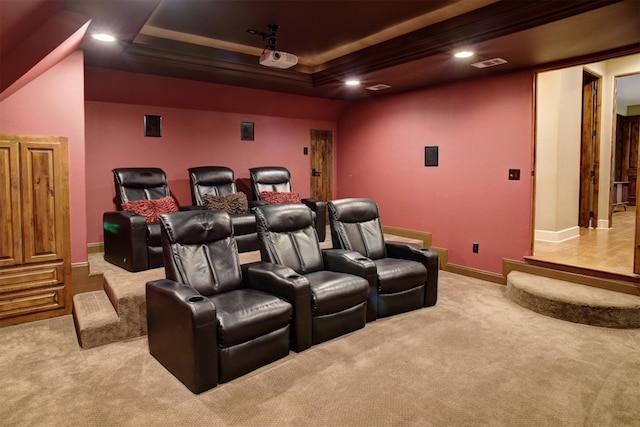 home theater room with a raised ceiling and light colored carpet