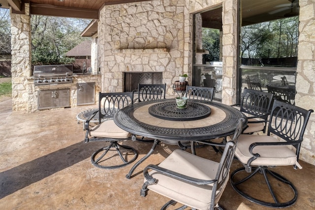 view of patio / terrace with area for grilling, an outdoor stone fireplace, and a grill