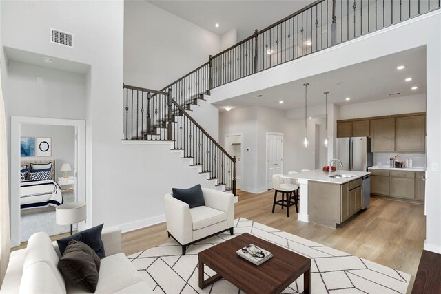 living room with sink, a high ceiling, and light hardwood / wood-style floors