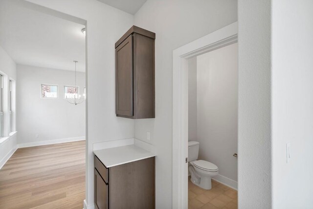 bathroom with wood-type flooring, toilet, and an inviting chandelier