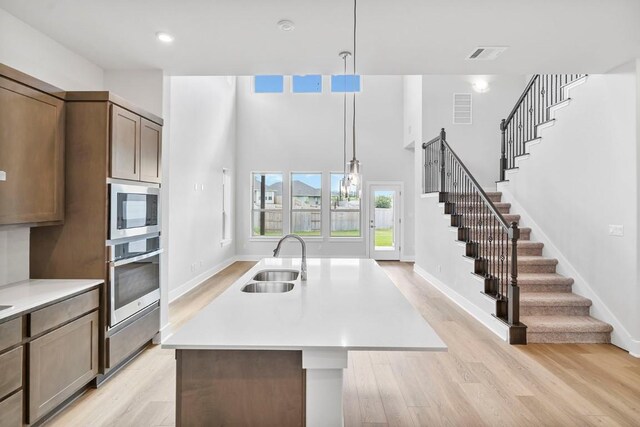 kitchen with pendant lighting, sink, appliances with stainless steel finishes, and a kitchen island with sink