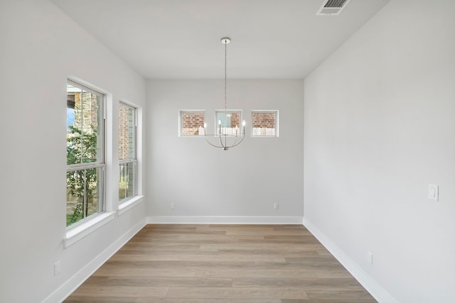 unfurnished dining area featuring light hardwood / wood-style flooring and a chandelier