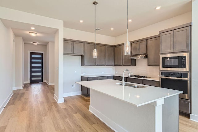 316 Chaste Tree Dr, San Marcos, TX 78666 - kitchen featuring appliances with stainless steel finishes, a sink, under cabinet range hood, light countertops, and decorative backsplash