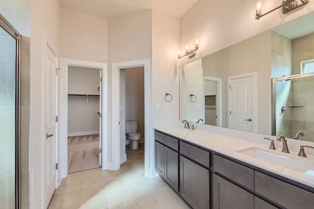 316 Chaste Tree Dr, San Marcos, TX 78666 - bathroom featuring a walk in closet, a stall shower, double vanity, toilet, and tile patterned floors