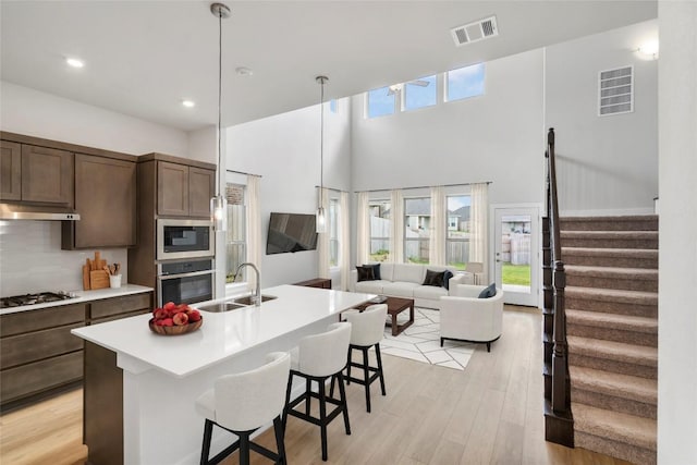 316 Chaste Tree Dr, San Marcos, TX 78666 - kitchen with stainless steel appliances, a sink, light wood finished floors, light countertops, and a breakfast bar area