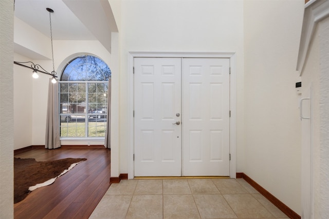 entrance foyer with light tile patterned floors, a high ceiling, and an inviting chandelier