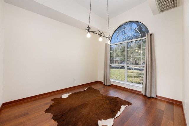 unfurnished dining area featuring vaulted ceiling and dark wood-type flooring